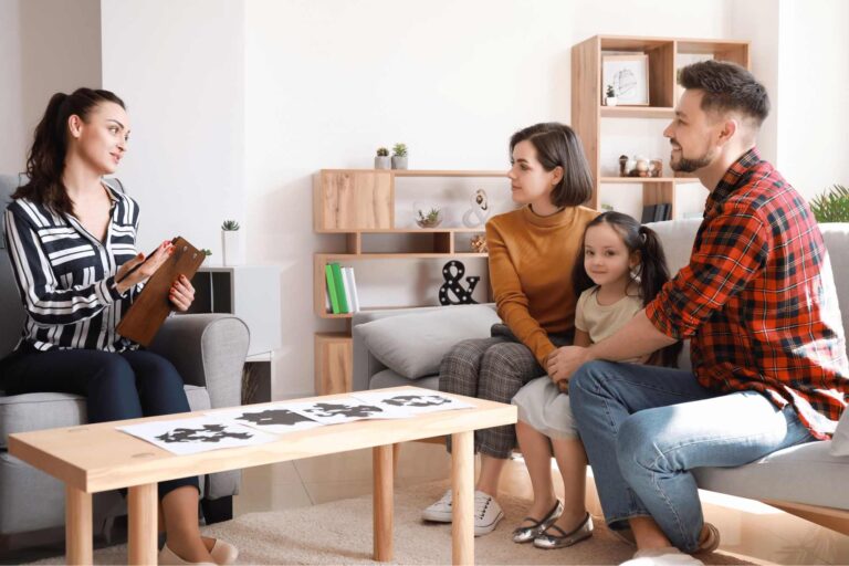 Behavior analyst explaining ABA therapy strategies to parents during a family intervention session