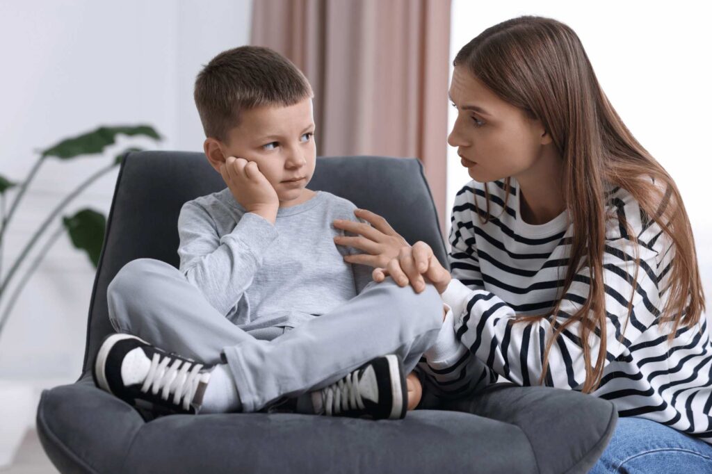 Mother talking to her son with autism during an emotional crisis, applying strategies on how to manage emotions calmly and consistently.