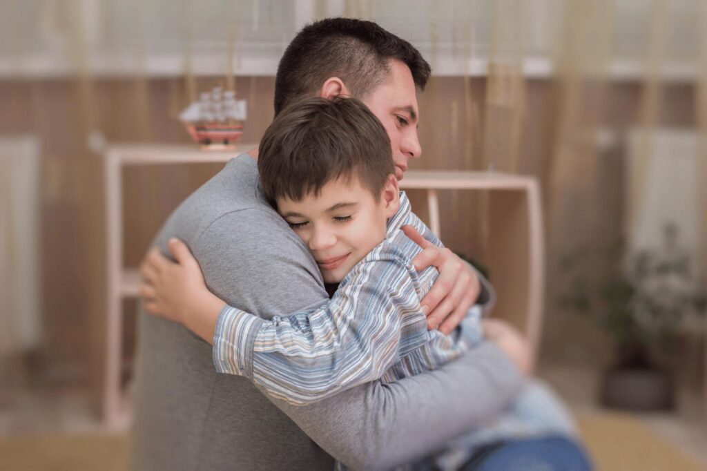 A father hugging his son with autism while using stress management techniques and reduce challenging behaviors at home