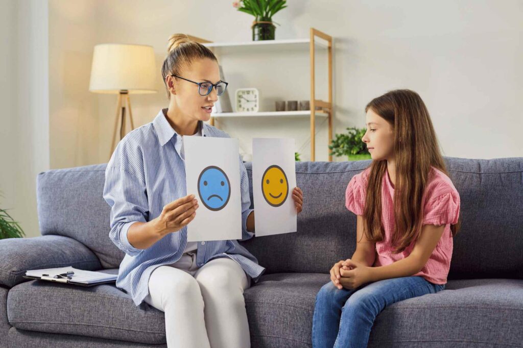 Therapist working with a girl in an ABA session to promote autism and friendship through social skills and communication.